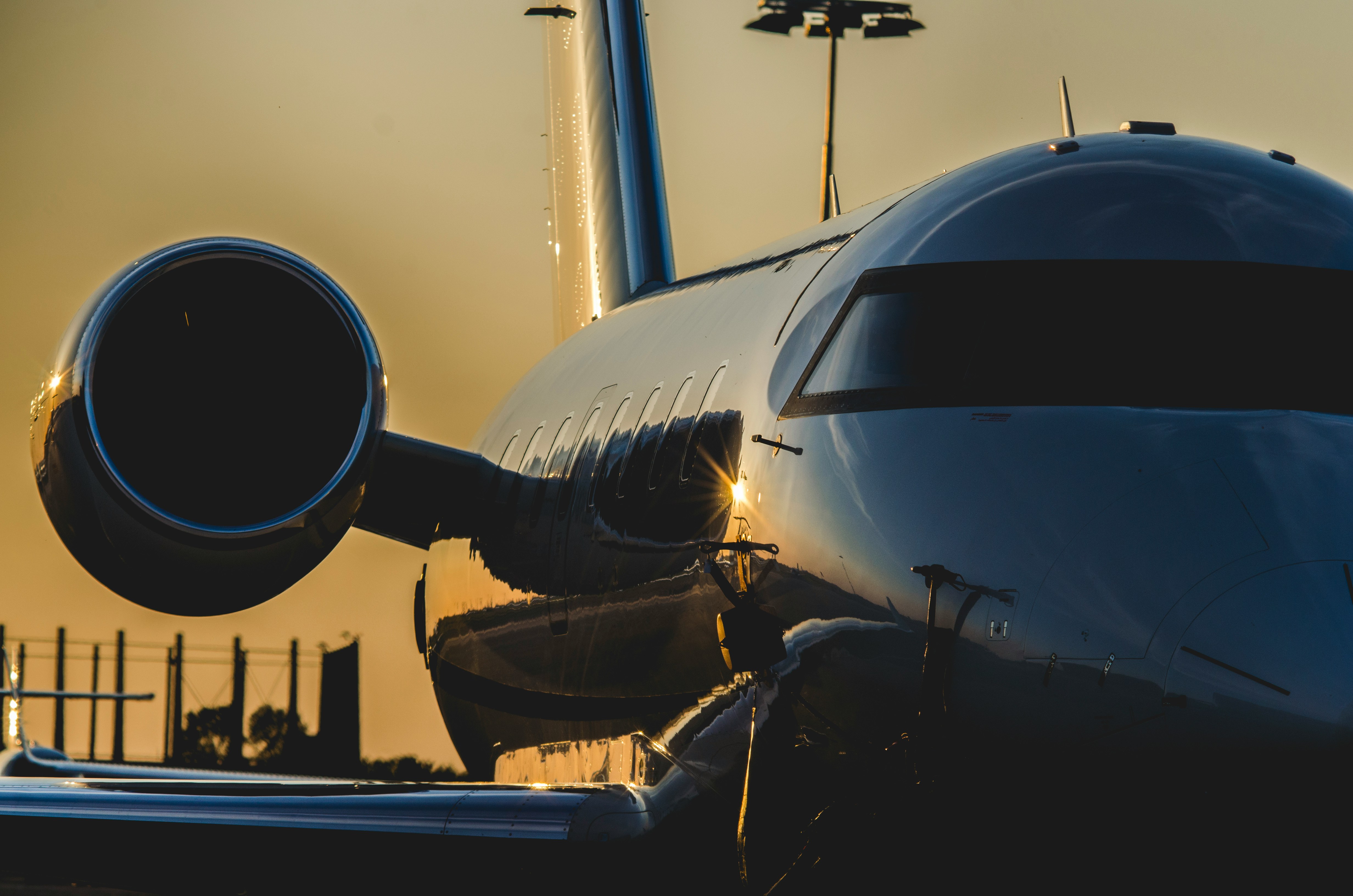 Sleek private jet engine and cockpit reflecting the warm, golden light of a sunset.